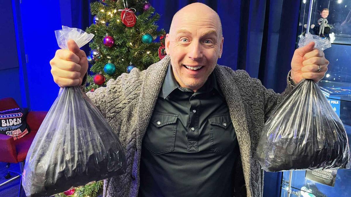 A photo of Mark Kaye holding two bags of coal