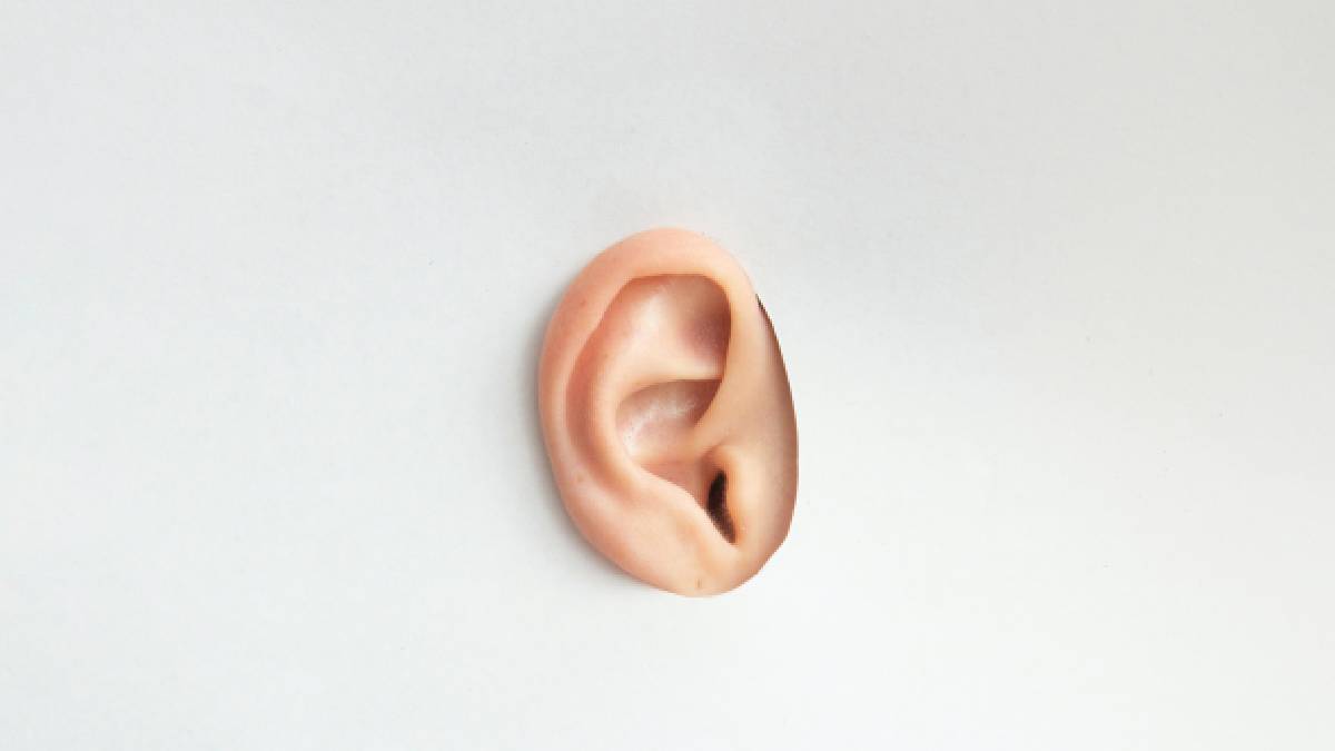 A photo of an ear through a cutout piece of paper