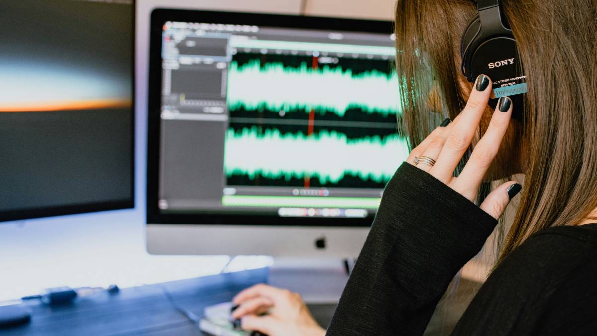 A photo of a woman wearing headphones editing audio